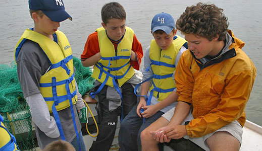 Instructor teaching group with the help of the school's historic wooden boats.